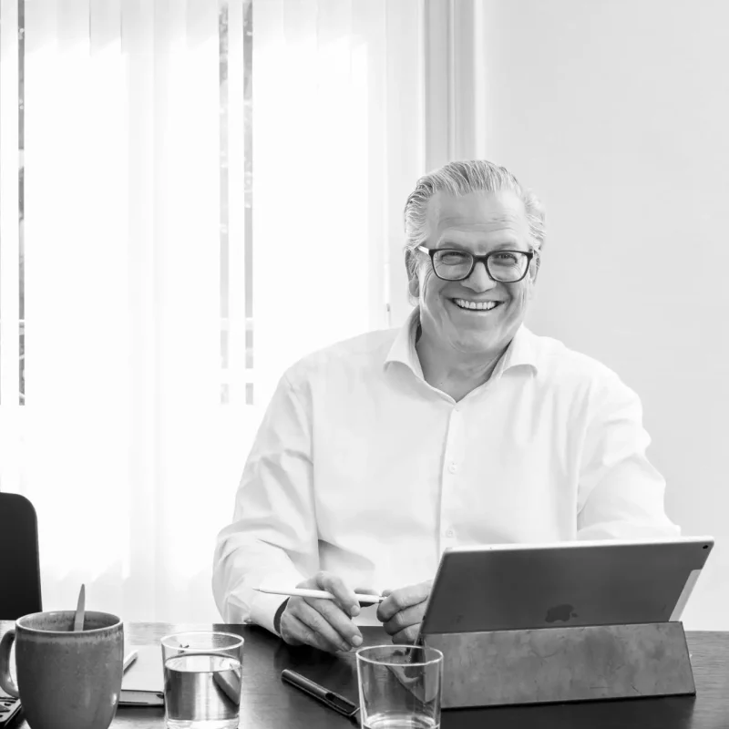 Dirk Spiegel im Gespräch bei Velaw, am Tisch mit Laptop und Unterlagen